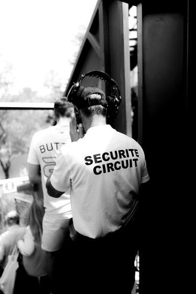 Sicherheitsmitarbeiter in einem T-Shirt mit der Aufschrift „SECURITY“ in einer Menschenmenge.